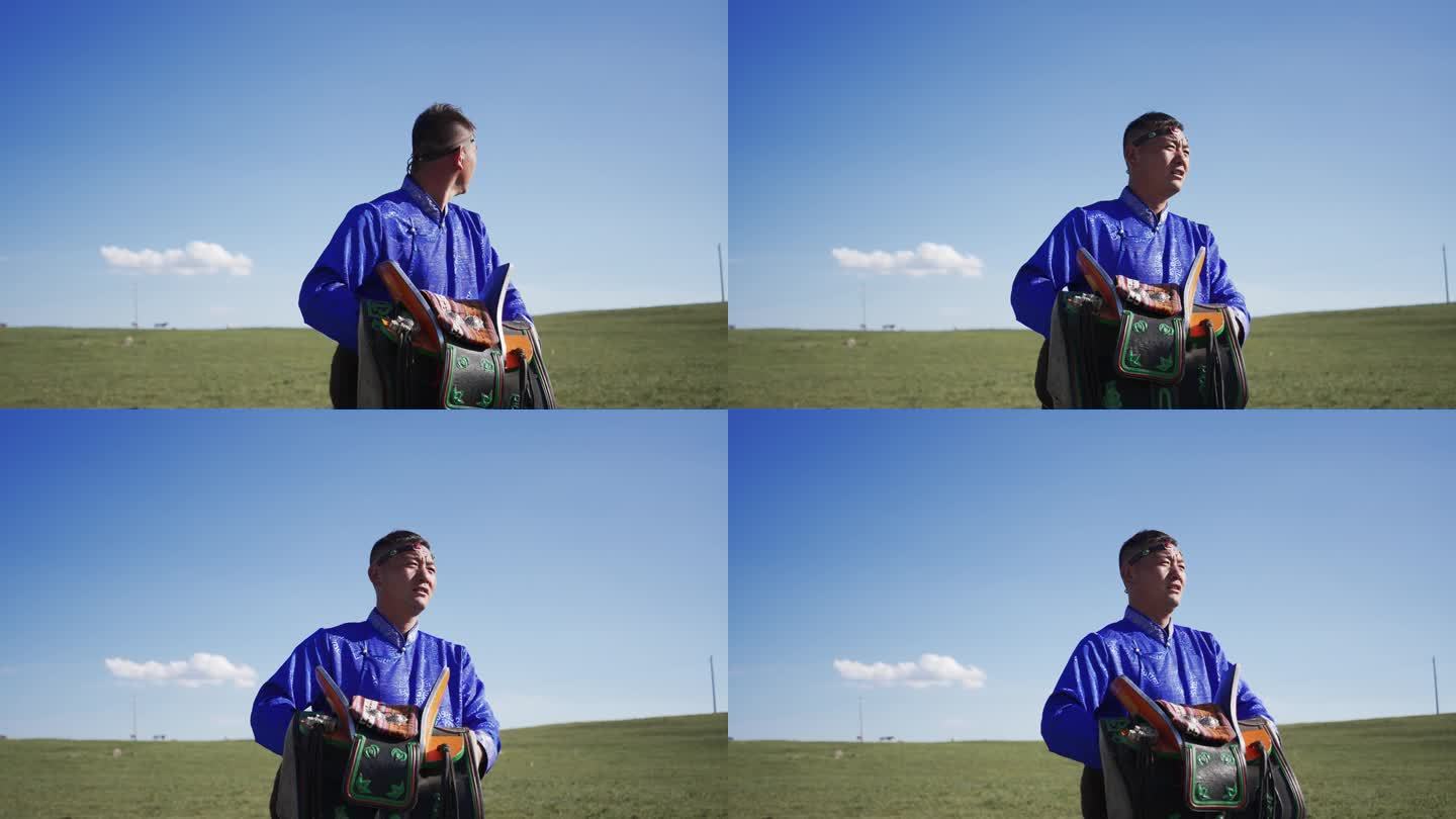 蒙古族牧民抱着马鞍走在草原上