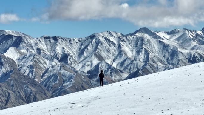 人在雪山下行走旱地拔葱运镜航拍镜头