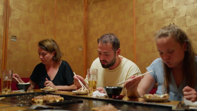 游客们在日式餐厅和居酒屋享受日本传统美食okonomiyaki