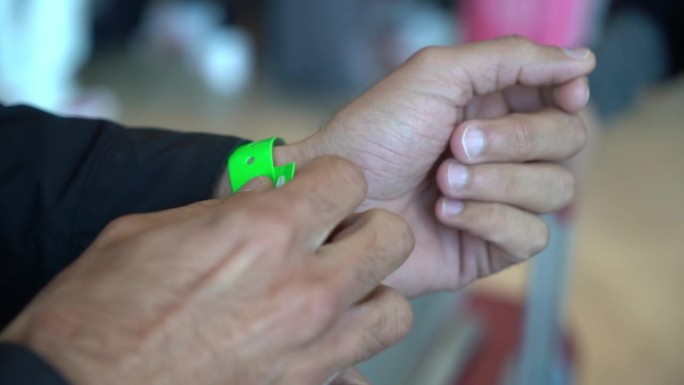 男性的手起初挣扎与事件手镯，但最终自豪地手势事件手镯上