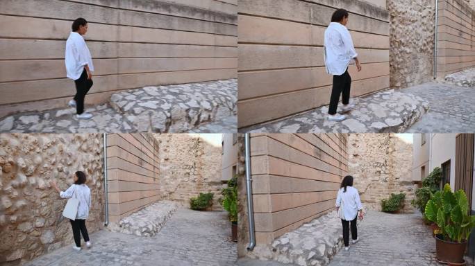 一名妇女沿着一堵大墙旁边的石头小路行走