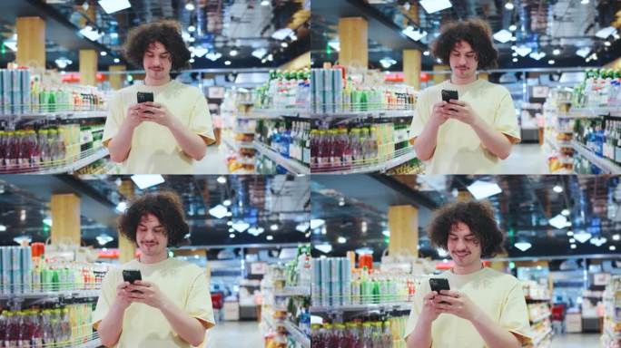 一个年轻人微笑着在杂货店摆满了五颜六色的饮料的过道里用他的智能手机，随意地为他充满活力的一天挑选饮料