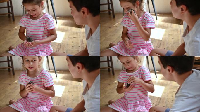 小女孩愉快地抱着一只小鸟，男孩在一旁观看，在舒适的室内环境中创造了童年好奇心和与动物联系的温馨时刻。