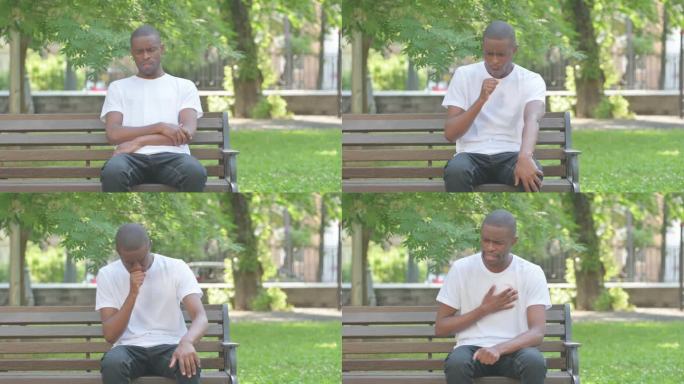 坐在公园长凳上咳嗽的非裔美国人