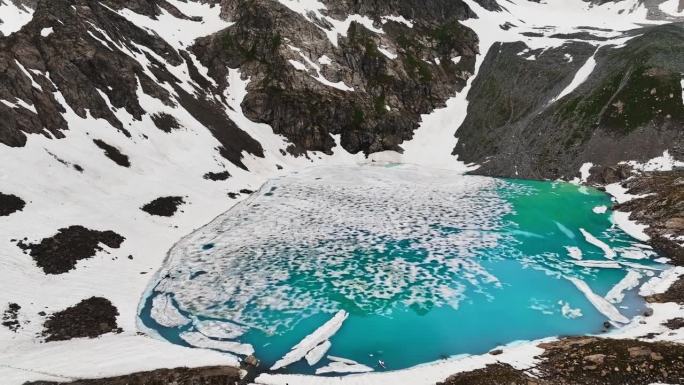 被雪崩袭击的高山湖泊当地的高原湖泊，在阴天被陡峭的山峰包围。鸟瞰图