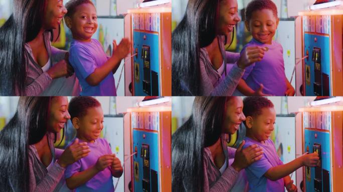 母亲帮助男孩在街机游戏中投币