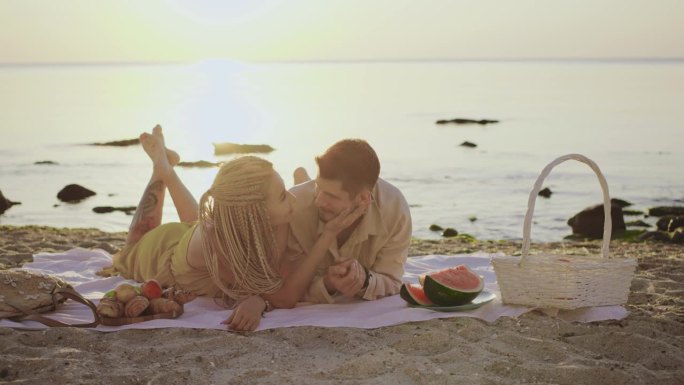 想象一下在日落时分浪漫的海滩野餐，一对夫妇拥抱在一起，品尝美味的食物和风景如画的风景，创造充满爱和欢