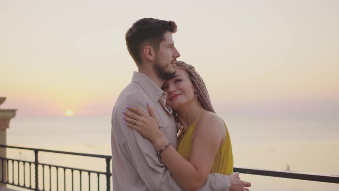 夕阳下的浪漫拥抱一对情侣在海边的亲密时刻，当太阳美丽地落在地平线上时，他们分享宁静和幸福的联系，创造