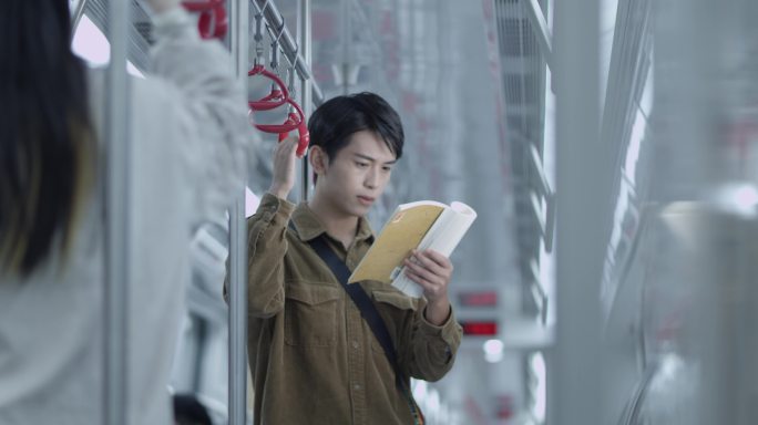 年轻男子在地铁上看书