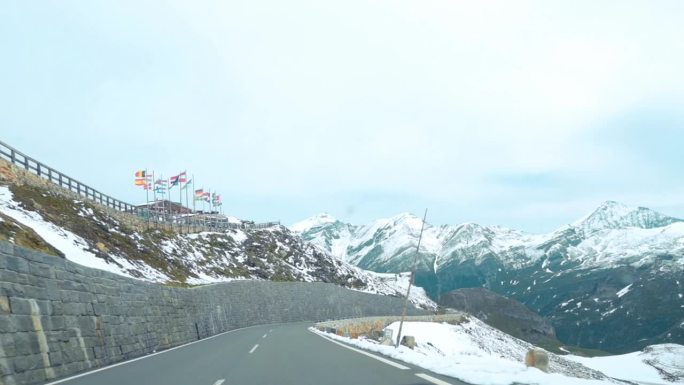 风景优美的山路蜿蜒穿过奥地利大格洛克纳的雪景，在远处可以看到白雪覆盖的山峰和高山地形的壮丽景色