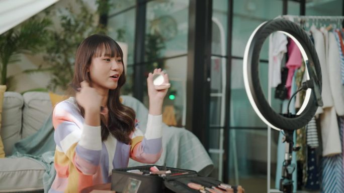 一名年轻的亚洲女子在直播中用化妆刷评价一款美容产品。