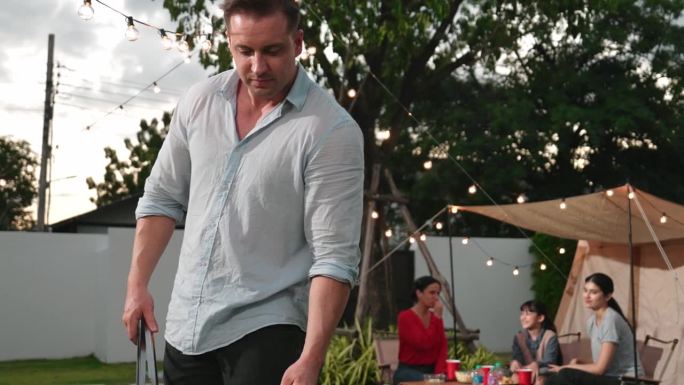 一家人一起在花园露营，中年父亲做烧烤。散度。