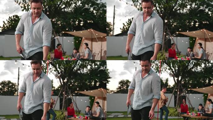 一家人一起在花园露营，中年父亲做烧烤。散度。