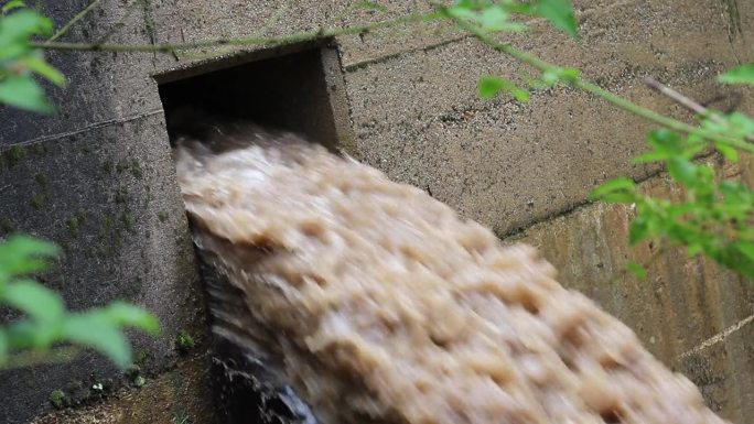 棕色的泥流从大坝吹出来