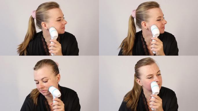 30多岁的女人用面部按摩器按摩自己的脸。面部护理