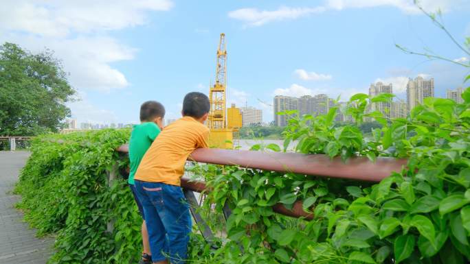 两个小孩在江边爬栏杆看风景