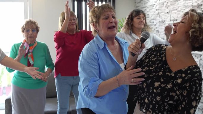 年长的朋友在家里开心地唱卡拉ok