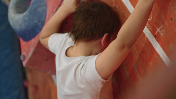 这个男孩有目的地爬上了陡峭的攀岩墙。
