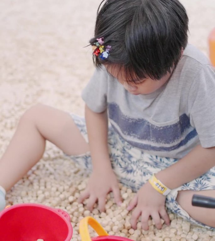 小男孩在室内操场上用玩具玩沙