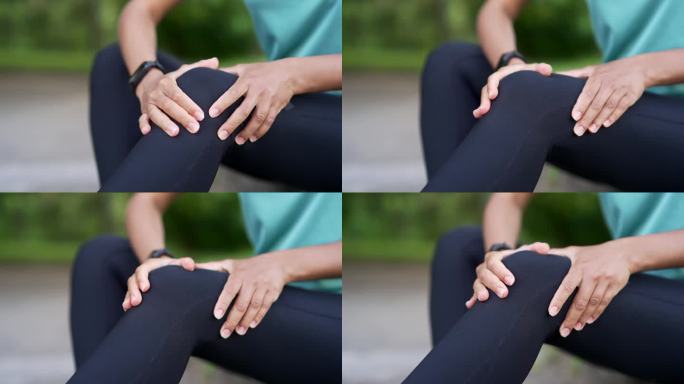 非裔美国女运动员在城市公园用手按摩膝盖腿部肌肉。黑人妇女遭受创伤。