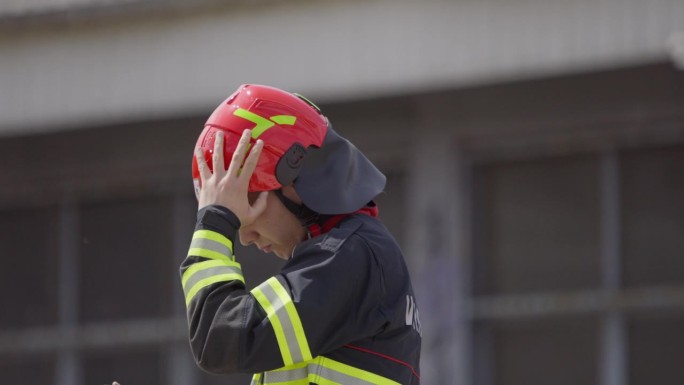 一名消防员在完成一次危险的救援任务后摘下头盔，象征着从火灾中救出受害者的英勇努力的结束，展示了他们在