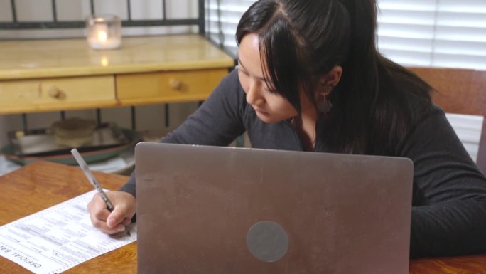 年轻漂亮的越南菲律宾混血妇女用手提电脑和邮寄选票，履行她在选举中投票的公民义务