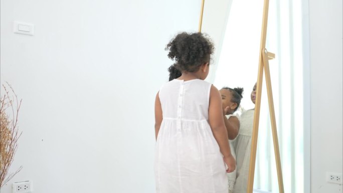 一个小女孩正在房子的试衣间里照镜子