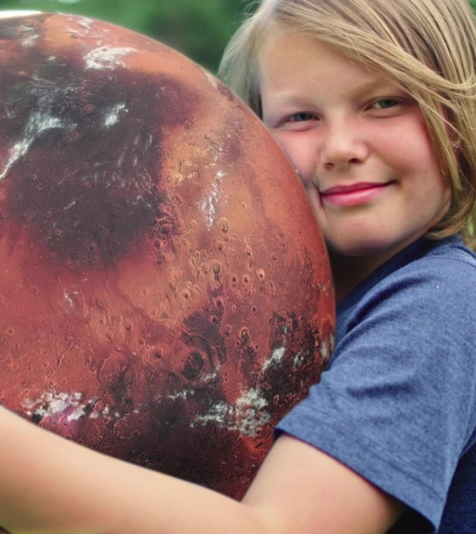 孩子抱着一个旋转的红色火星地球仪