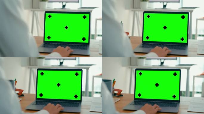 年轻的亚洲女商人在现代办公室工作时使用绿屏笔记本电脑的特写。色度关键技术，营销设计。