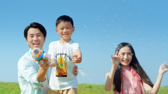 幸福一家三口男孩玩泡泡机露营阳光蓝天大树