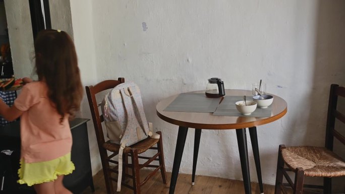 母亲和女儿穿着休闲的衣服，在舒适的家庭用餐区摆桌子吃饭，享受在一起的美好时光。