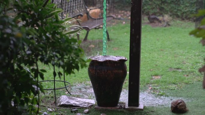 下雨了，花园的场景，陶瓷罐从屋顶的排水沟收集雨水。