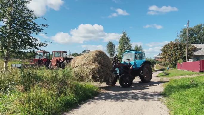 一幅风景优美的乡村风景画上，一辆蓝色拖拉机在尘土飞扬的小路上蜿蜒前行