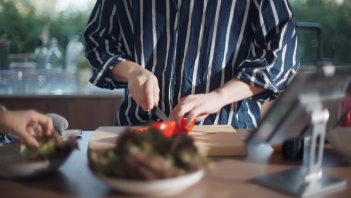 一个亚洲男人和朋友在家里的厨房里一起准备食物和沙拉。