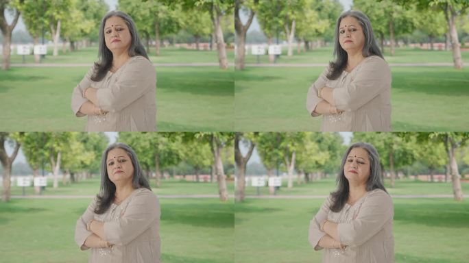 印度老妇人双手交叉站在公园里的肖像