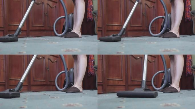 穿着拖鞋正在用吸尘器清洁地板的女人的腿。