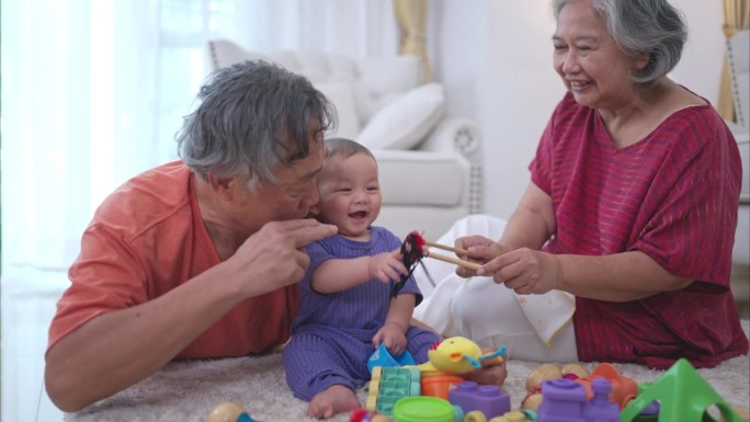 爷爷奶奶和他们的小孙子在房子的客厅里快乐地玩耍