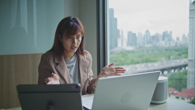 亚洲女商人在办公室用耳机开视频会议