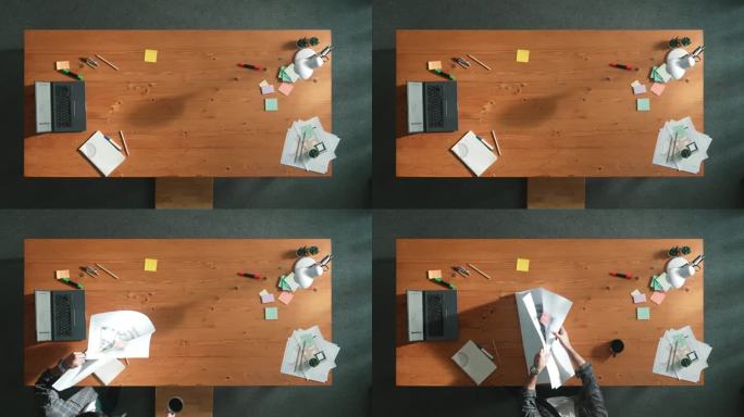 项目经理持有项目计划并在表格中打开的自顶向下视图。研讨会。