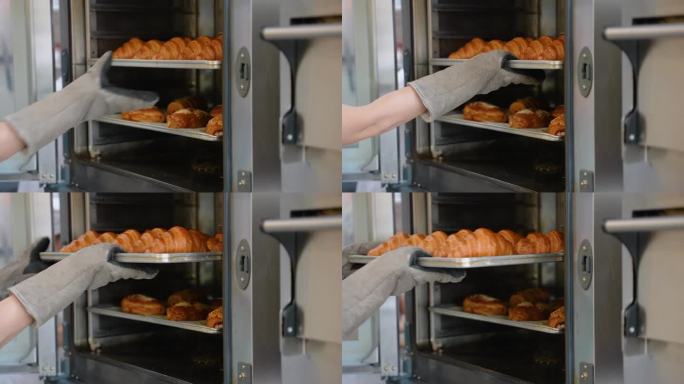 面包师将准备好的面包和牛角面包放入专业烤箱