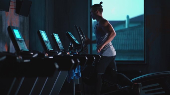 在现代健身房里的跑步机上跑步的英俊活跃的男人