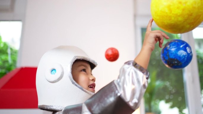 穿着太空服的女孩在家里玩耍，探索和学习行星，想象太空旅行。