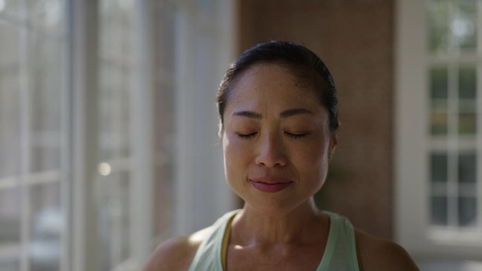 一名微笑的女子在空旷的大房间里练习瑜伽时对着镜头摆姿势