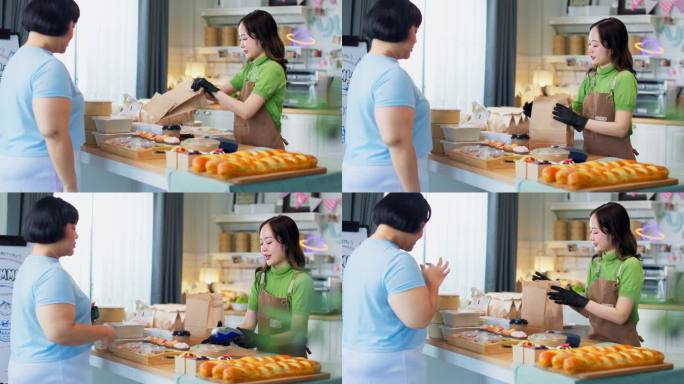 年轻的亚洲女顾客用手机为装满新鲜出炉的食品的纸袋付款。NFC二维码设备，payWave，非接触式支付