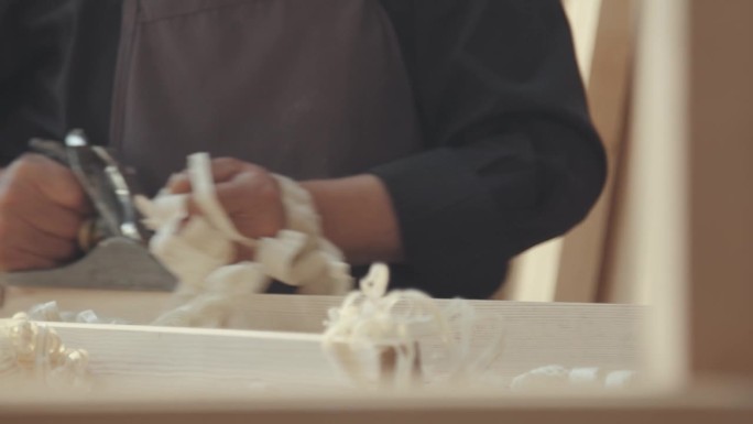 老木匠正在用刨木机刨木头