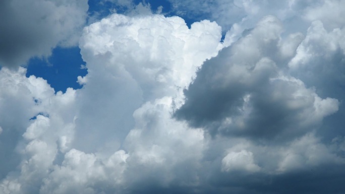 美丽的白色和黑色的风暴云在蓝天。体积效应。对流层中的对流。延时。低层的积云，蓬松的，像棉花一样。毛茸