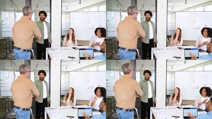 一名身穿米色衬衫的男子笑容满面地与一名同事握手，象征着一个友好合作的工作场所