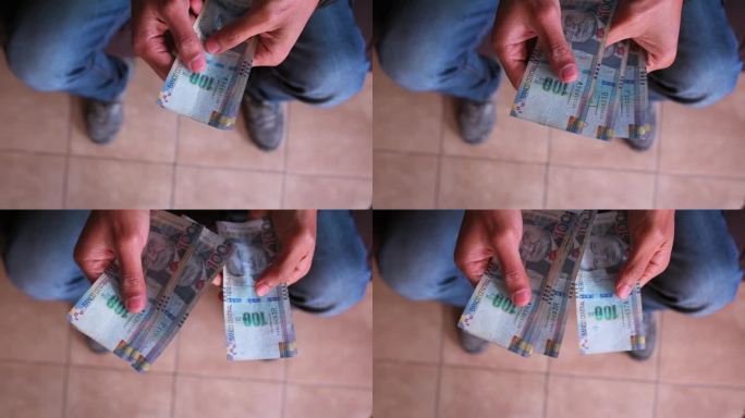 从上面看，一个男人的手在数100个鞋底的钞票。