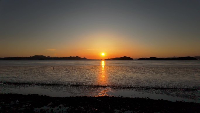 海边夕阳下赶海人在海里赶海抓海鲜