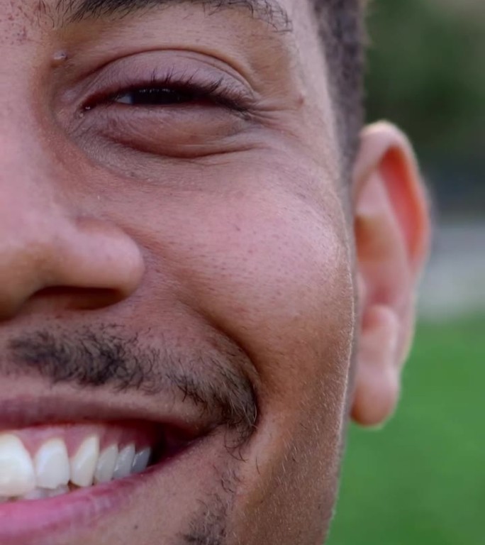 快乐的非裔美国年轻人站在城市公园的特写肖像。